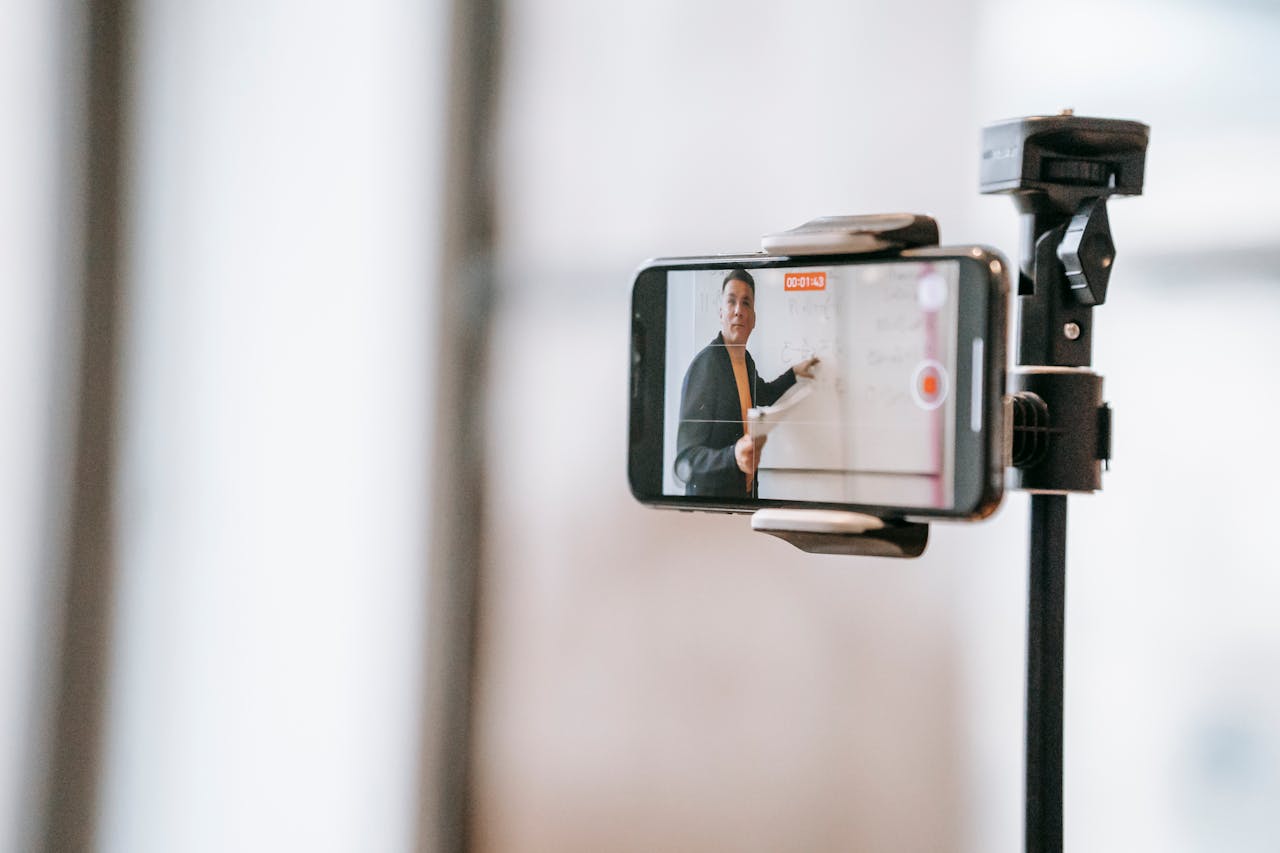 A lecturer conducting an online class using a smartphone mounted on a tripod.